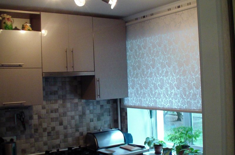 Светлая рулонная штора на окне маленькой кухни