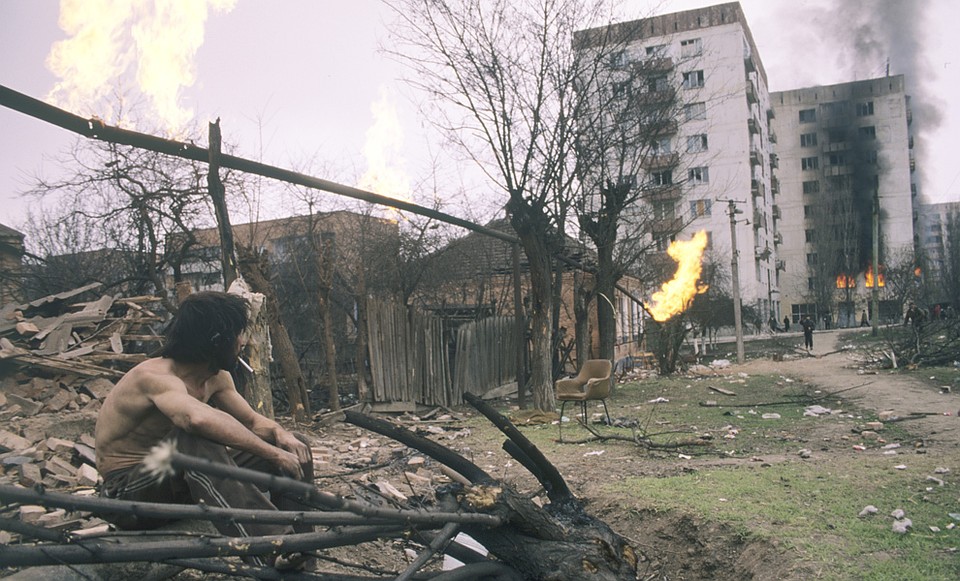 Житель Грозного смотрит на остатки своего дома на фоне пробитой осколками газовой трубы Фото: РИА Новости